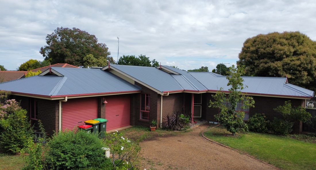 Suburban home roof repainted a clean grey green